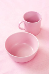 Pink cup and plate on gentle pink cloth background