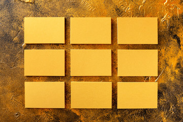 Mockup of nine blank golden foil horizontal business cards at golden textured background.