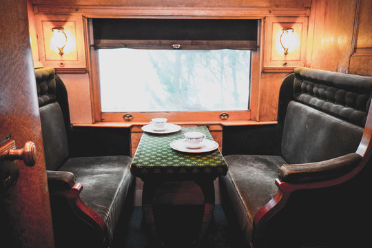 Travelling inside a luxurious vintage train carriage, private room with window view. Tea set served on table