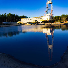 reflection of the drilling rig in the water summer forest