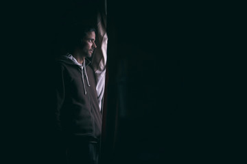 Man in the dark looking through a window