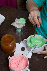 Woman fills a pastry bag with cream. Cream of different colors for decorating cake Basket. Nearby is a jar of jam.