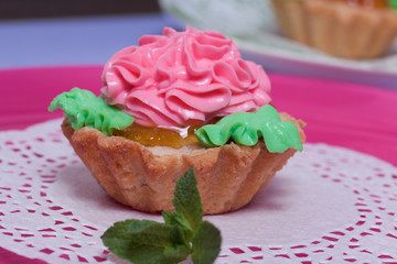 Basket cake decorated with cream of different colors. Stuffing from jam. Decorated with mint leaves.