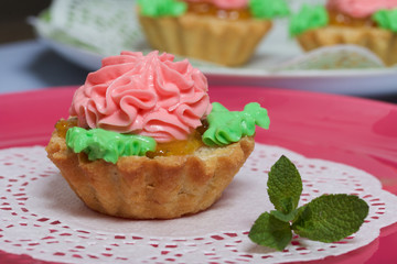 Basket cake decorated with cream of different colors. Stuffing from jam. Decorated with mint leaves.