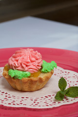 Basket cake decorated with cream of different colors. Stuffing from jam. Decorated with mint leaves.