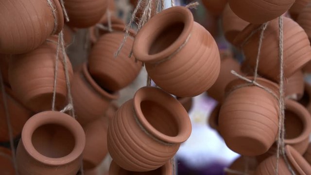 Closeup of clay ceramic pots hanging on ropes and fluttering on wind