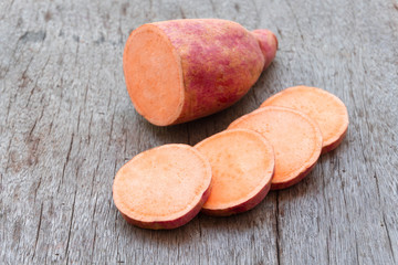 Sweet potato with slices on wooden background, raw food