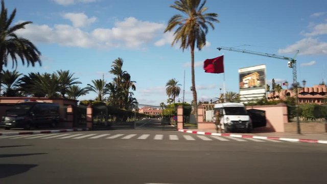 Driving past guarded government remises with lots of Moroccan flags, Marrakech. Morocco.