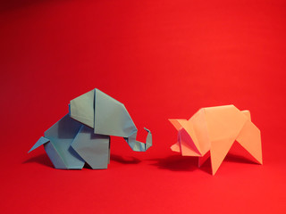 Origami blue elephant and pink pig on a red background