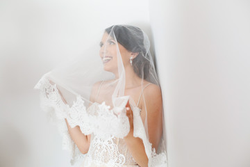 A brunette bride with a veil smiles at the camera
