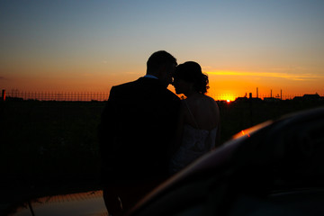 Beautiful wedding couple watching the sunset in a convertible car.