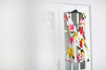 Beautiful colored dress hanged on white door