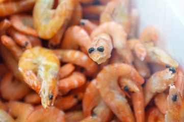 Cheerful happy big-eyed frozen shrimp on the background of a pile of red shrimp. Shrimp in ice in the fridge. Concept of the correct and tasty choice of sea food for the family. Trendy style