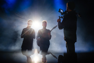 Camera man filming music video clip for musicians in low light