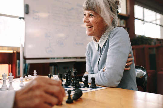 Senior woman playing chess in a classroom