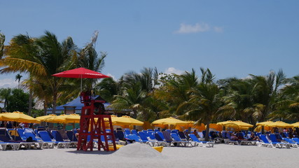 HARVEST CAYE, BELIZE - 16 May 2017: A lifeguard sits on top of a high chair with a red umbrella at...