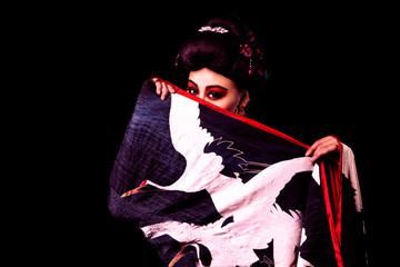 beautiful Japanese girl in kimono with a fan on a black background