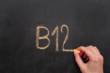 Man writing word B12 on chalkboard