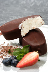 chocolate butter ice cream popsicles on the white plate with fresh summer berries, strawberries, blueberries