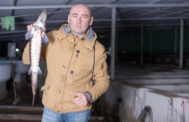 Owner of sturgeon farm showing fish indoors