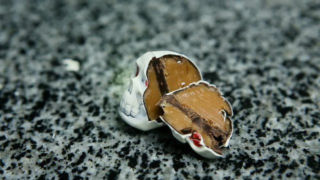 sliced in half chocolate candy in skeleton skull shape with red eyes lie on kitchen table