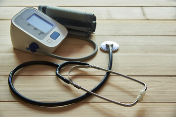 A stethoscope and sphygmomanometer on wooden background