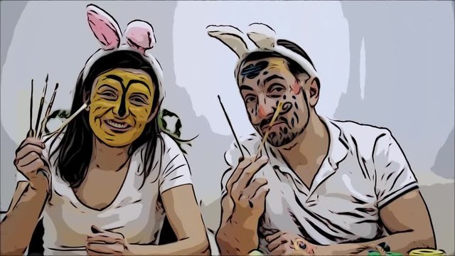 Cute and adorable couple came back to childhood. Man is holding two paint-brushes in his hands and a woman is holding four paint-brushes in her. Couple wearing bunny ears. They are making funny