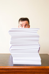 Caucasian businessman behind a stack of paper