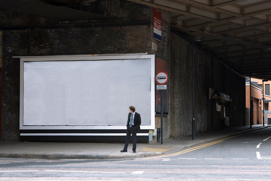 A businessman looking at a blank billboard
