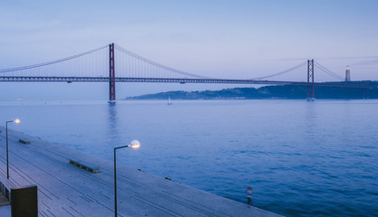 Fototapeta na wymiar Landmark 25 of April bridge on Tagus River with Cristo Rei in background, Lisbon, Portugal