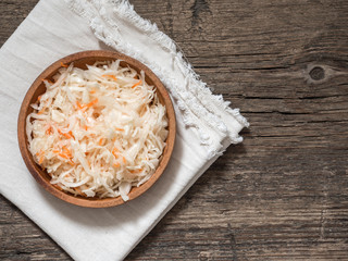 Sauerkraut. Fermented cabbage in a brown clay plate on a wooden table. Healthy vegetarian food and best natural probiotic