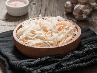 Sauerkraut. Fermented cabbage in a brown clay plate on a wooden table. Healthy vegetarian food and best natural probiotic
