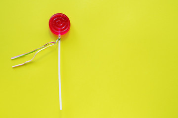 Round candy Lollipop of red color on a yellow background. Sweet background.