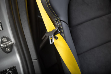 Close up of yellow seat belt on black car seat