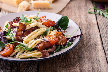 Handmade fusilli pasta with pancetta, roasted cherry tomatoes and fresh green vegetables