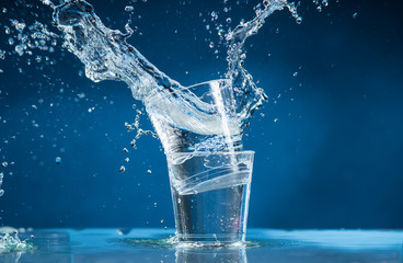 falling small glasses and spilling water on a blue background