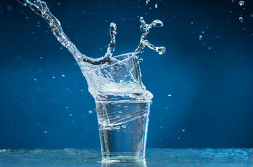 falling small glasses and spilling water on a blue background