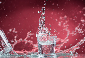 falling small glasses and spilling water on a red background