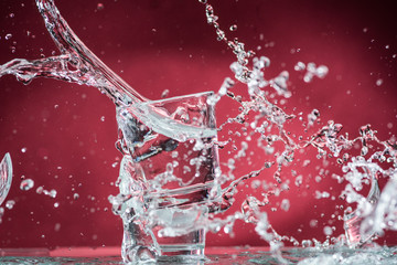 falling small glasses and spilling water on a red background