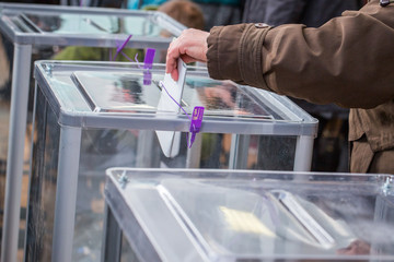 Illustrative image of the election in a democratic society. Elections in Ukraine. The process of voting at a polling station. The voter throws the ballots in the ballot box.