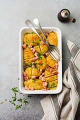 Baked potatoes with ham, herbs and breadcrumbs on gray light background. Scandinavian cuisine. Top view.