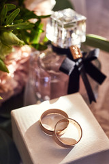 wedding rings lie on the table near a wedding bouquet