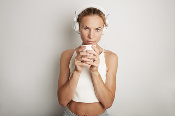 Portrait Handsome Young Woman Listening Music Player Headphones Blank White Background.Pretty Girl looking Holding Coffe Cup Hands Empty Wall.Beauty Lifestyle Fashion Hipster People Abstract Concept.