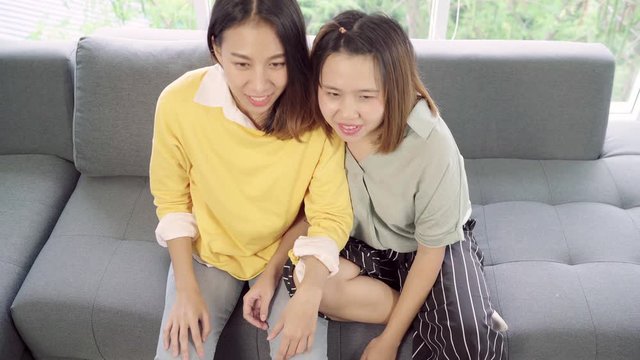 Asian women cheer football match in front of television living room at home, funny friends enjoy funny moment while lying on the sofa when relaxed at home. Lifestyle women relax at home concept.