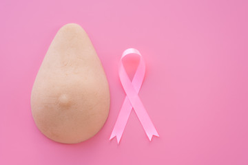 Breast model and pink ribbon on blue background.Health education for breast self exam (BSE).Breast cancer awareness and self check, healthy lifestyle concept.Breast cancer symbol