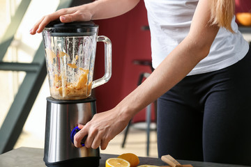 Young woman making healthy smoothie at home