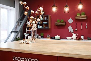 Vase with cotton branches on table in modern kitchen