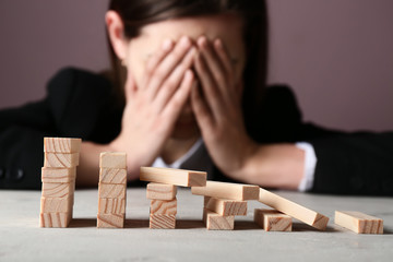 Stressed woman with destroyed blocks on light table. Concept of career failure