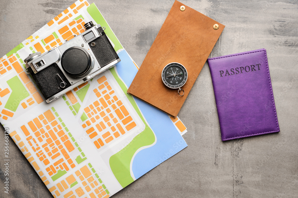 Wall mural map with compass, photo camera and passport on grey table