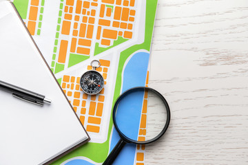 Map with compass and magnifier on white table